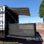 white and black travel trailer with extended awning and mesh privacy screen deployed outdoors