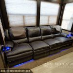 Luxury RV theater seating with black leather reclining chairs, blue ambient lighting, and multi-panel windows with cellular shades
