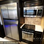 RV kitchen featuring stainless steel refrigerator with blue accent lighting, microwave, and marble backsplash