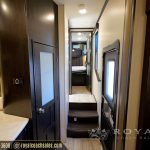 RV interior layout showing hallway with dark wood finishes, multiple windows, and access to bedroom area