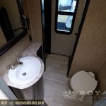 RV bathroom with round white sink, marble countertop, toilet, wood-grain walls, mirror, and exit door with window