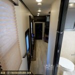 RV interior hallway with pleated window shade, wooden flooring, and bedroom entrance