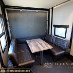 RV dining area with brown quilted booth seating and wooden table with blackout shades