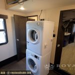 RV laundry room with stacked white washer and dryer units between windows and storage