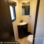 RV bathroom interior with dark vanity cabinet, round sink, mirror, and window