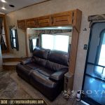 RV interior lounge area featuring leather seating, built-in windows, wooden storage cabinets, and entrance door