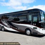 burgundy and white Class A motorhome with bold graphic design viewed from side angle in parking lot