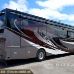 burgundy and white Class A motorhome with desert landscape graphics parked at Royal Coach Sales lot