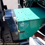 Green Cummins generator and blue cooler mounted in RV exterior storage compartment