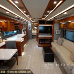 Full interior view of luxury motorhome showing kitchen, living area, fireplace and entertainment system