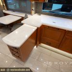 RV dining area with white countertop, dinette seating, windows with blinds, and wood cabinetry