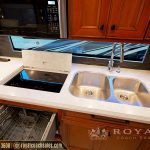 Modern RV kitchen countertop with dual stainless steel sink, induction cooktop, and dishwasher