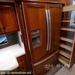 RV kitchen area featuring wooden cabinetry, stainless steel refrigerator with ice maker, and open shelving