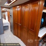 Luxury RV hallway with wood cabinetry, tile flooring, bedroom visible through doorway, and storage closets