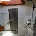 Spacious RV shower with marble tile walls, dark gray tile accents, chrome fixtures, and showerhead