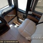 RV cab interior with beige leather seats, windows with blinds, and control panels